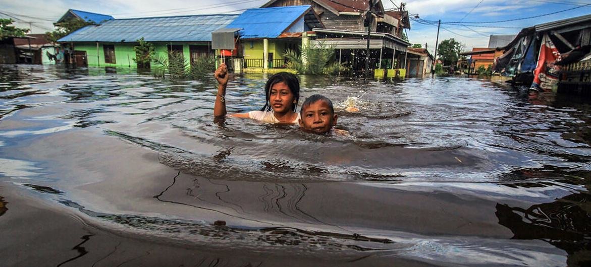 © Greenpeace/Pram Children wade through flood water in Palangka Raya, in Central Kalimantan, Indonesia.